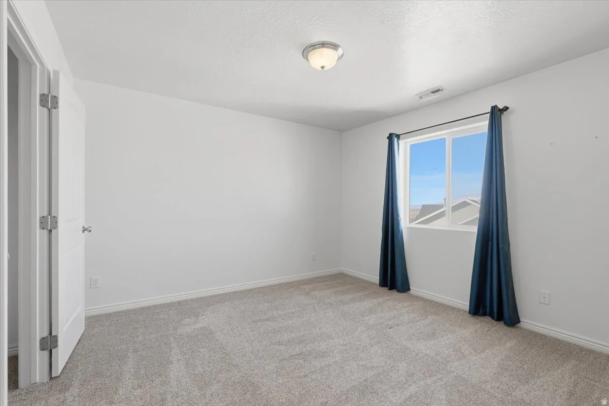 Empty room with light carpet and a textured ceiling