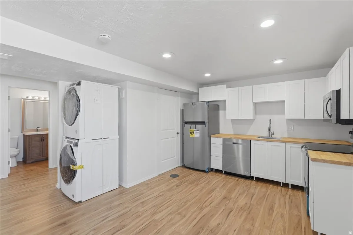 Kitchen with stainless steel appliances, white cabinets, light wood-style floors, and recessed lighting