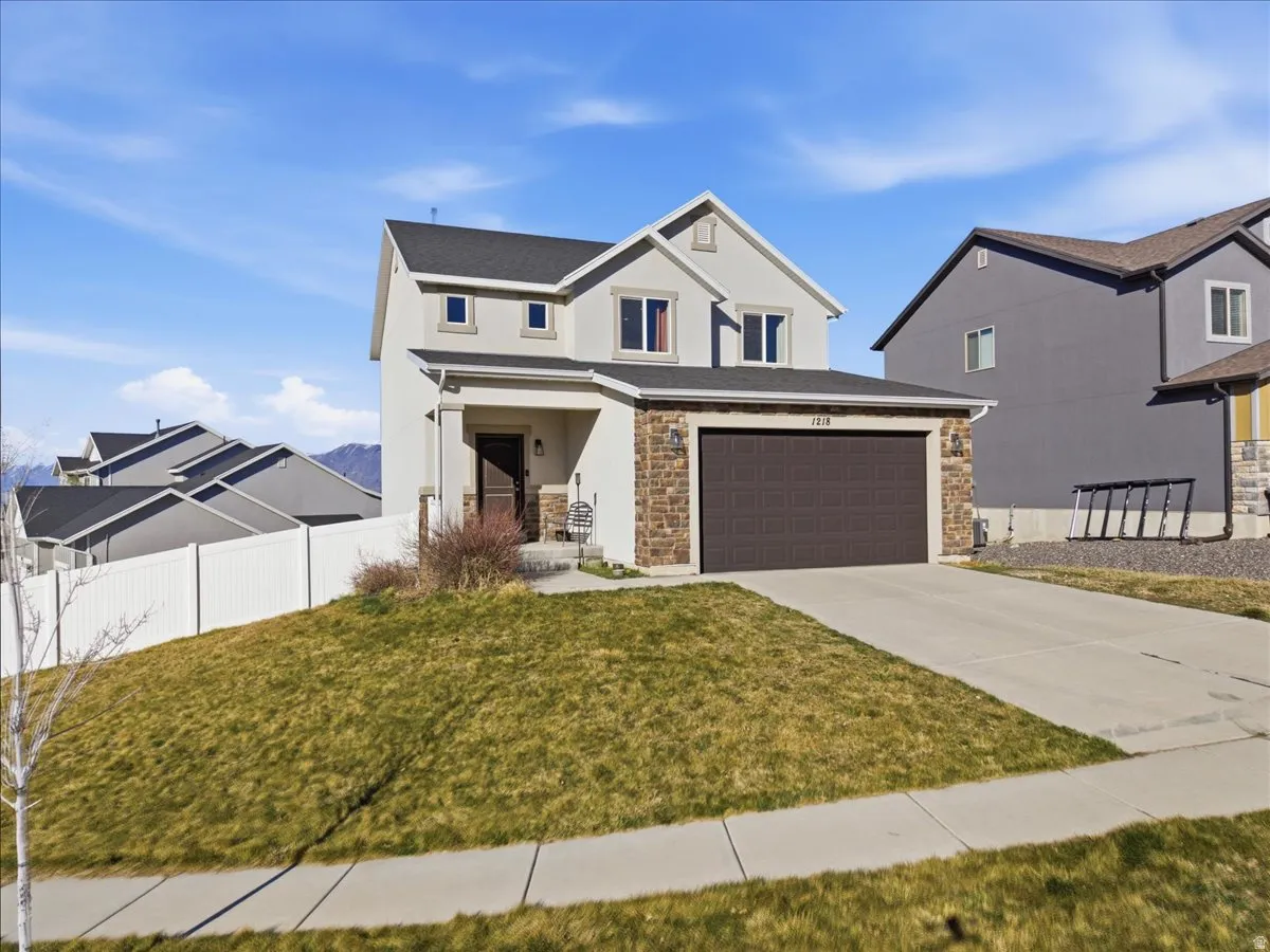 View of front of property featuring concrete driveway, stucco siding, and stone siding
