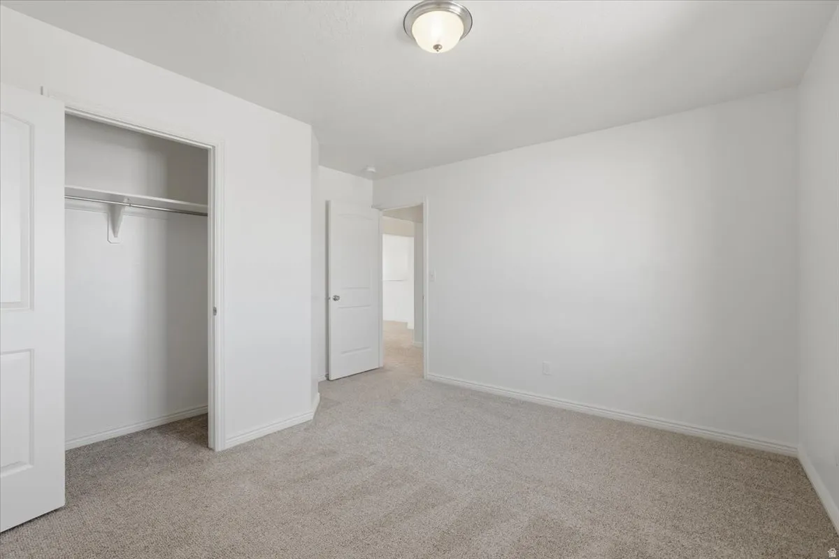 Unfurnished bedroom featuring light carpet and a closet