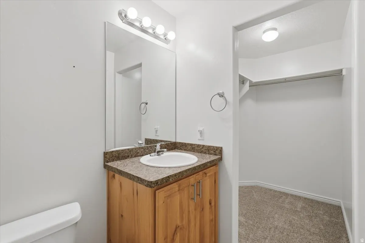 Bathroom with vanity, carpet floors, and a walk in closet