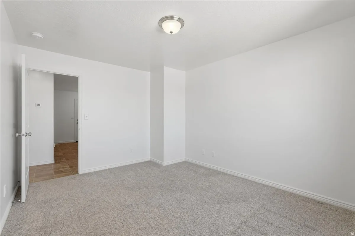 Spare room with baseboards and light carpet