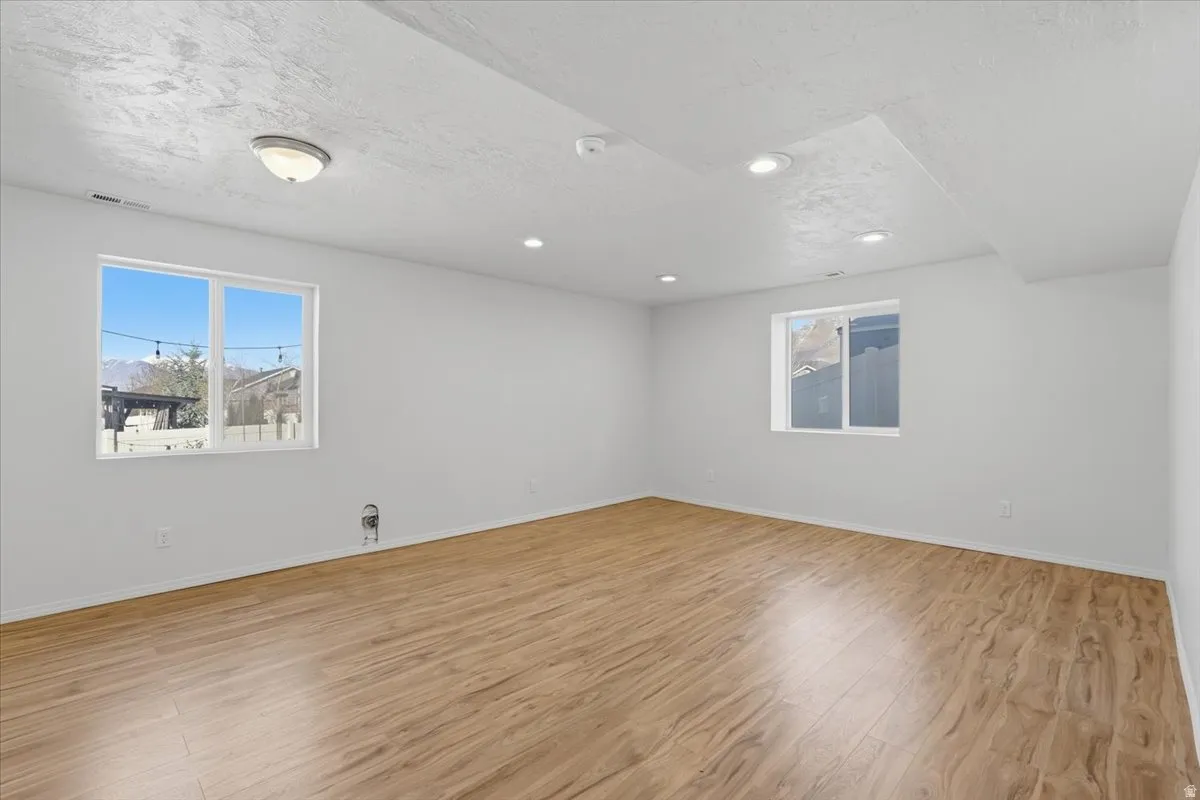 Empty room featuring light wood finished floors and a textured ceiling