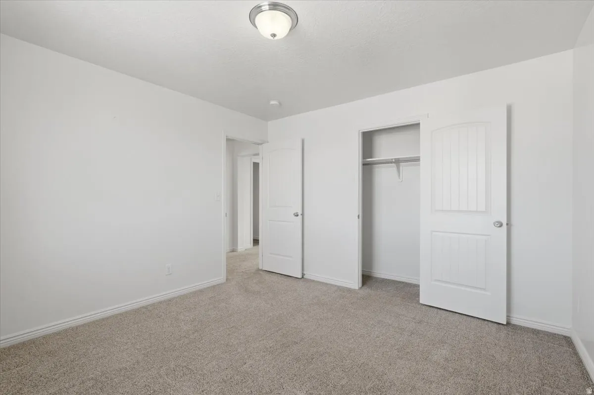 Unfurnished bedroom featuring light carpet and a closet