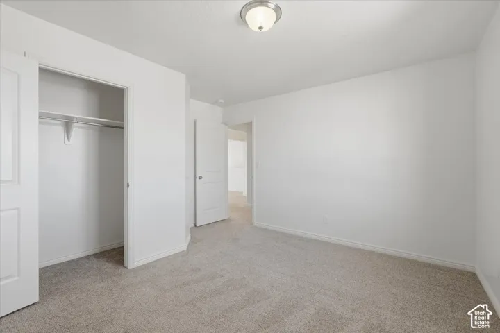 Unfurnished bedroom featuring light carpet and a closet