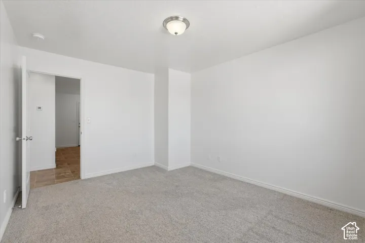 Spare room with baseboards and light carpet