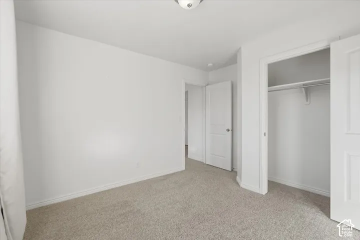 Unfurnished bedroom featuring light carpet and a closet