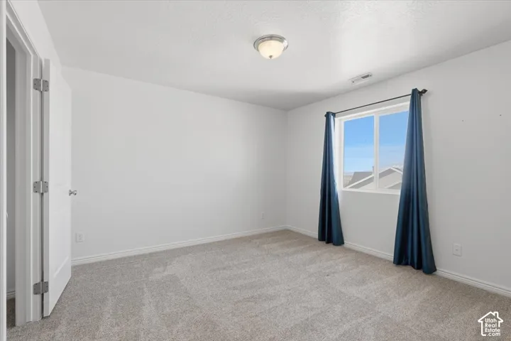 Empty room with light carpet and a textured ceiling