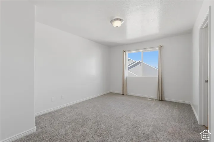 Unfurnished room with light colored carpet and a textured ceiling