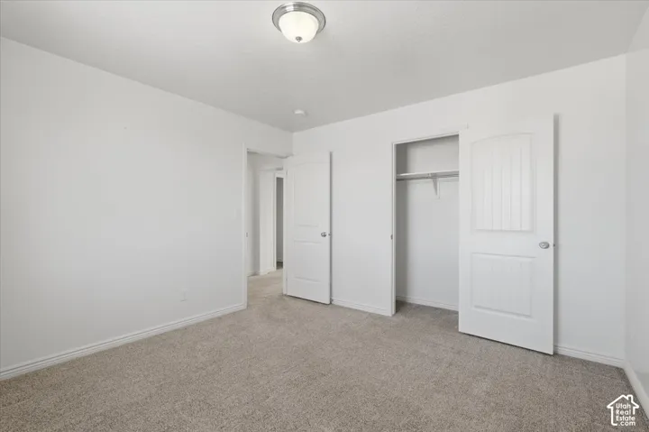 Unfurnished bedroom featuring light carpet and a closet