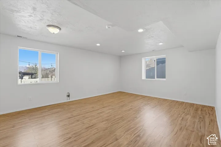 Empty room featuring light wood finished floors and a textured ceiling