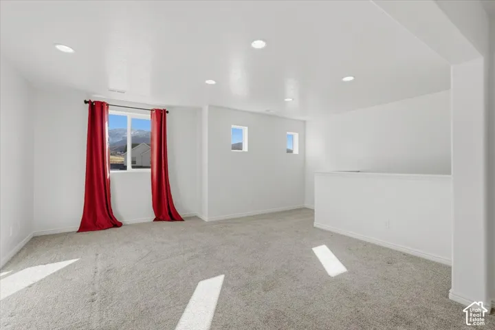 Empty room with light carpet and recessed lighting