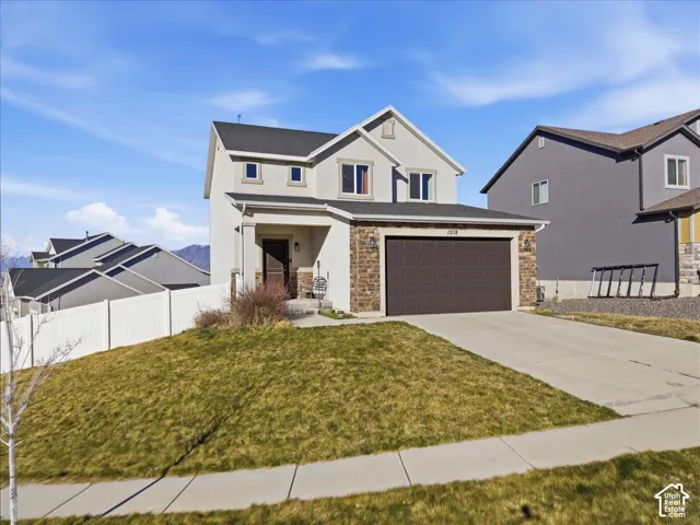 View of front of property featuring concrete driveway, stucco siding, and stone siding