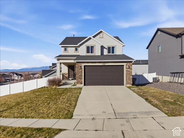 Traditional-style home featuring a porch, concrete driveway, an attached garage, and stone siding