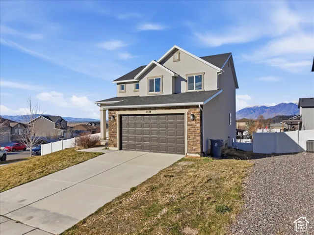 Traditional home with stucco siding, concrete driveway, stone siding, a mountain view, and a residential view