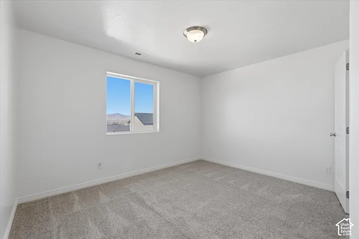 Unfurnished room featuring light carpet and baseboards