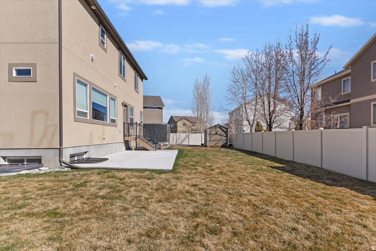 Fenced backyard with a storage unit, a patio, and a residential view