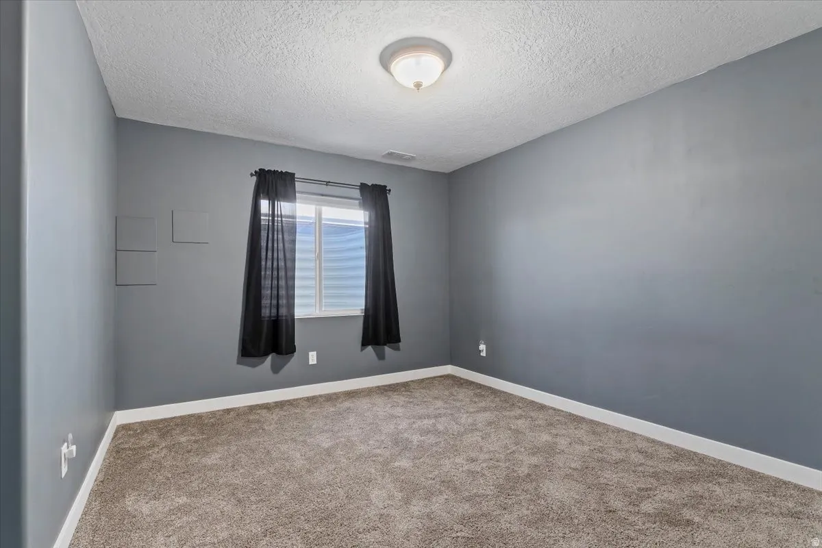 Unfurnished room with carpet and a textured ceiling