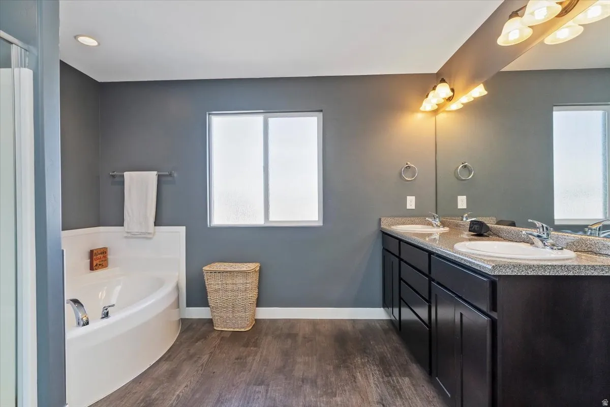 Bathroom featuring double vanity, a garden tub, and dark wood-type flooring