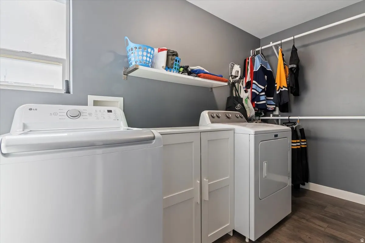 Laundry area with dark wood-type flooring, washing machine and clothes dryer, and cabinet space