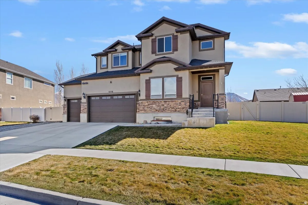 View of front of house with a gate, stucco siding, concrete driveway, stone siding, and an attached garage