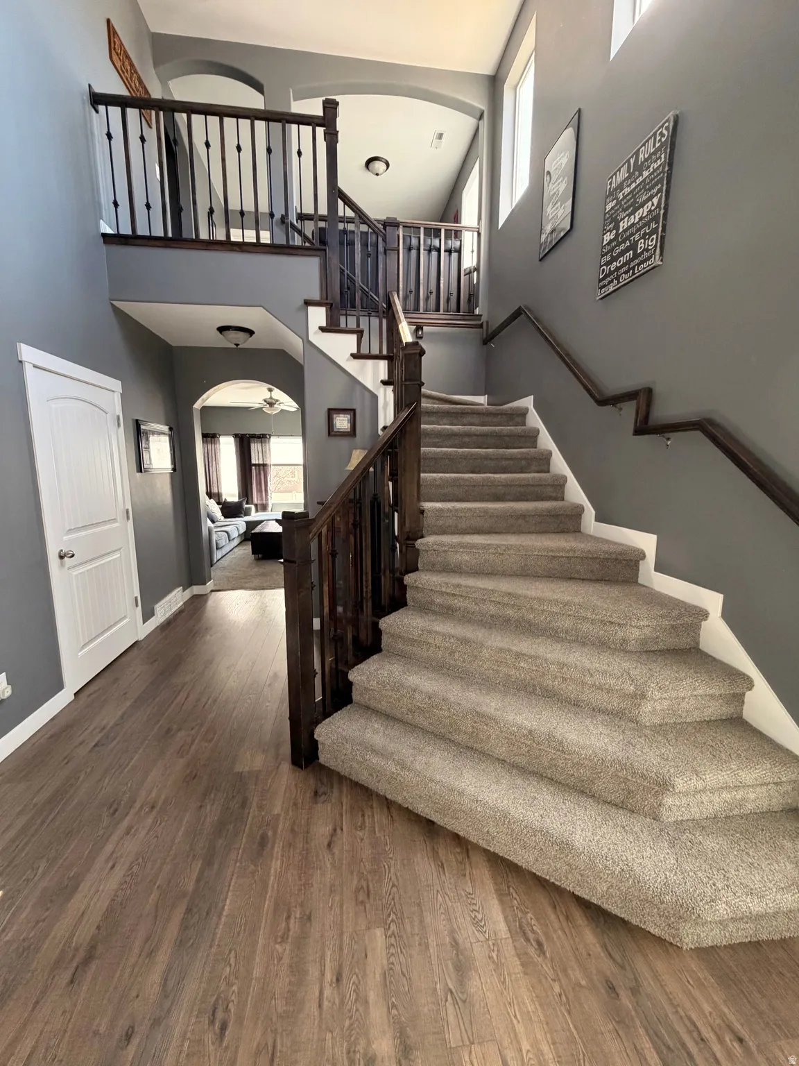 Stairway with arched walkways, wood finished floors, and a high ceiling