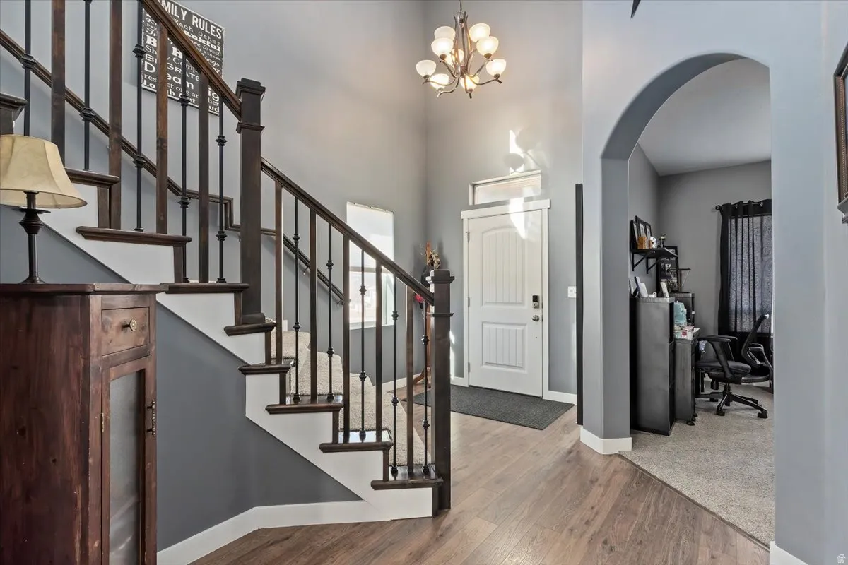 Foyer entrance with arched walkways, wood finished floors, suspended lighting, and a high ceiling