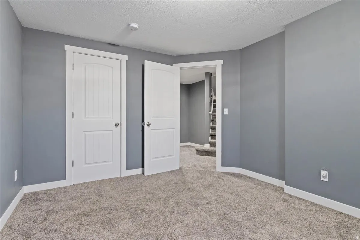 Unfurnished bedroom featuring light colored carpet and a textured ceiling