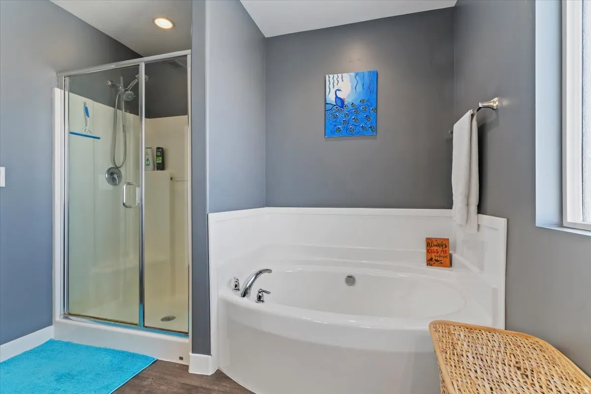 Bathroom with a shower stall, a garden tub, and dark wood-type flooring