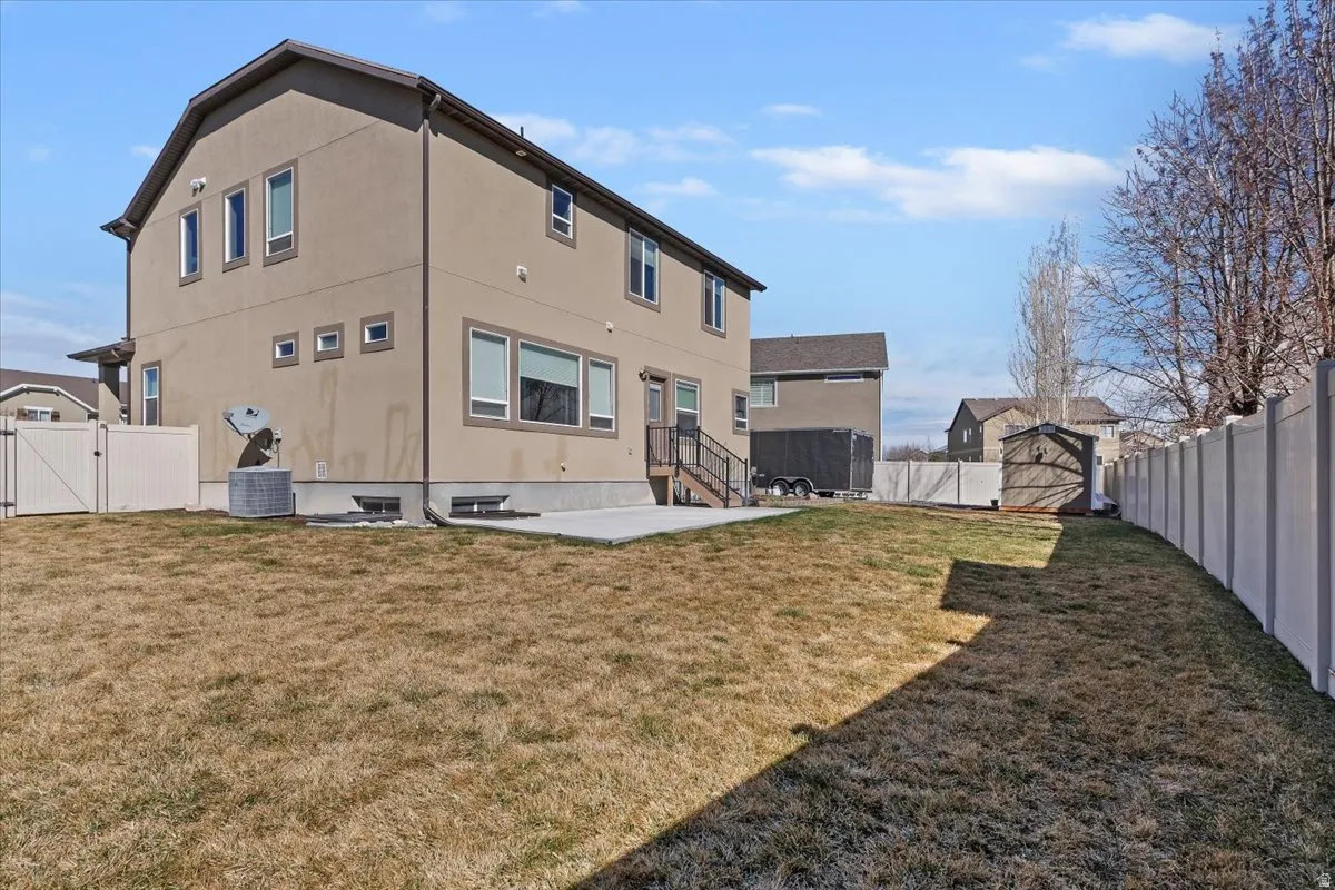 Back of house featuring a gate, a fenced backyard, a patio, stucco siding, and entry steps