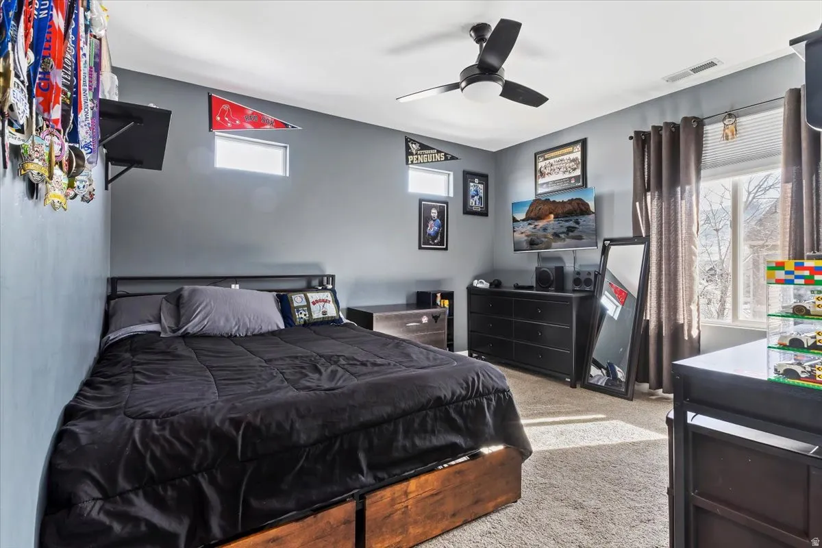 Carpeted bedroom featuring ceiling fan