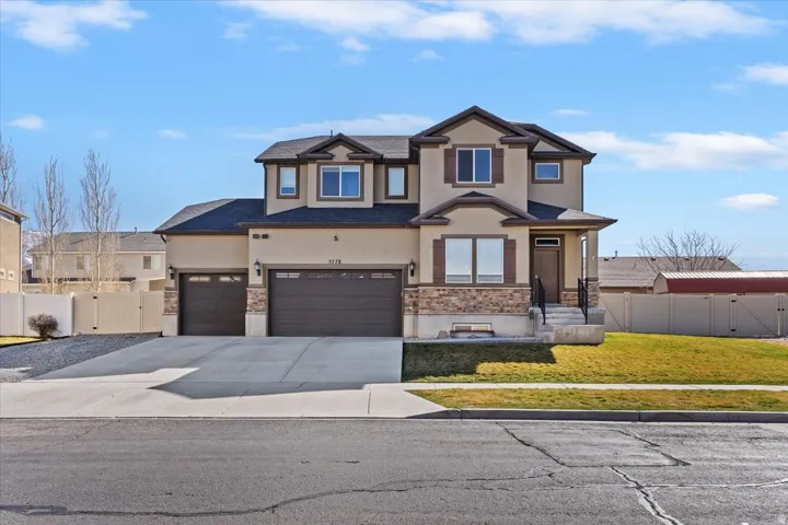 Craftsman-style home with a gate, stucco siding, stone siding, driveway, and a garage