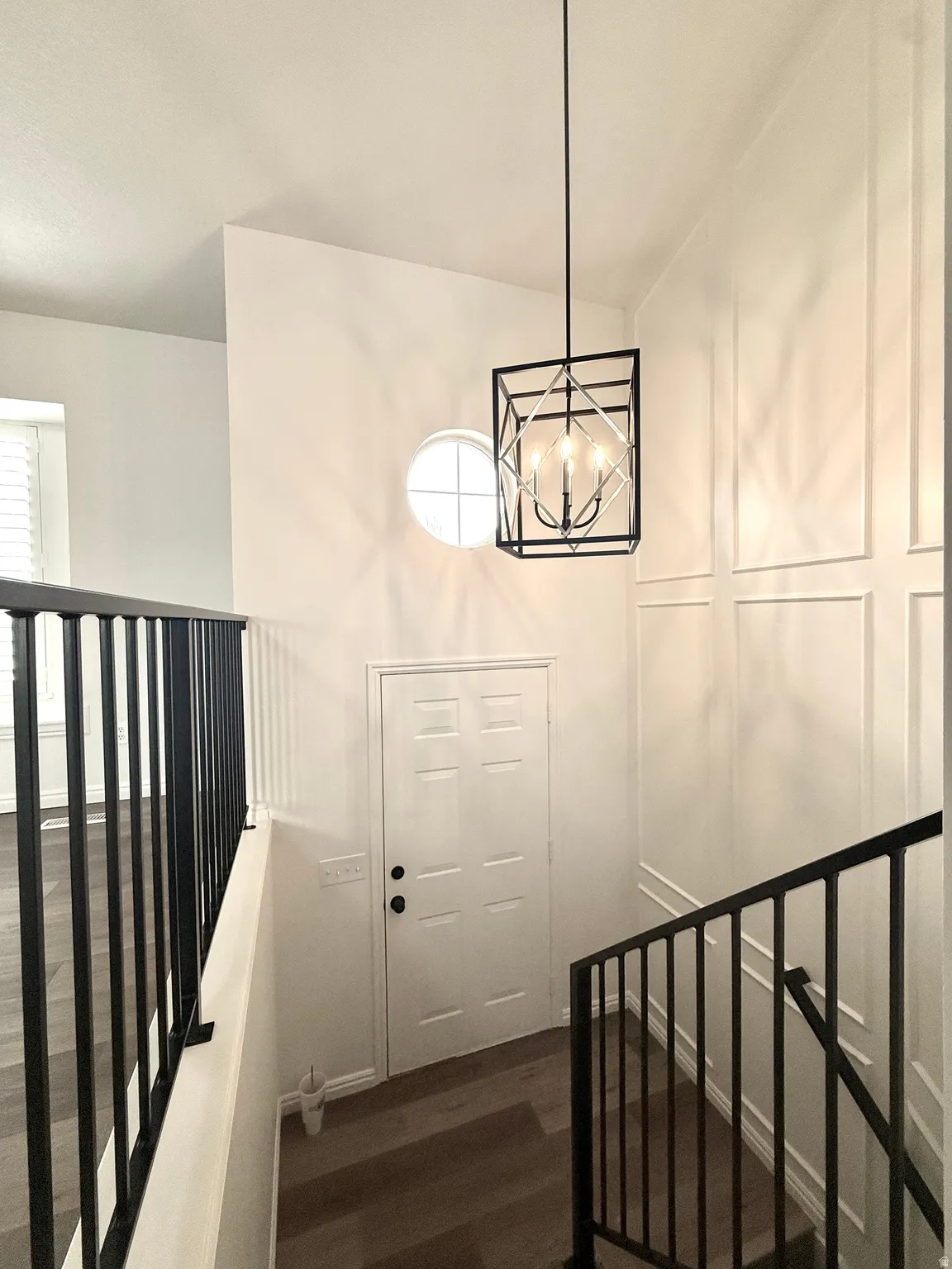 Stairs with wood finished floors and hanging lights