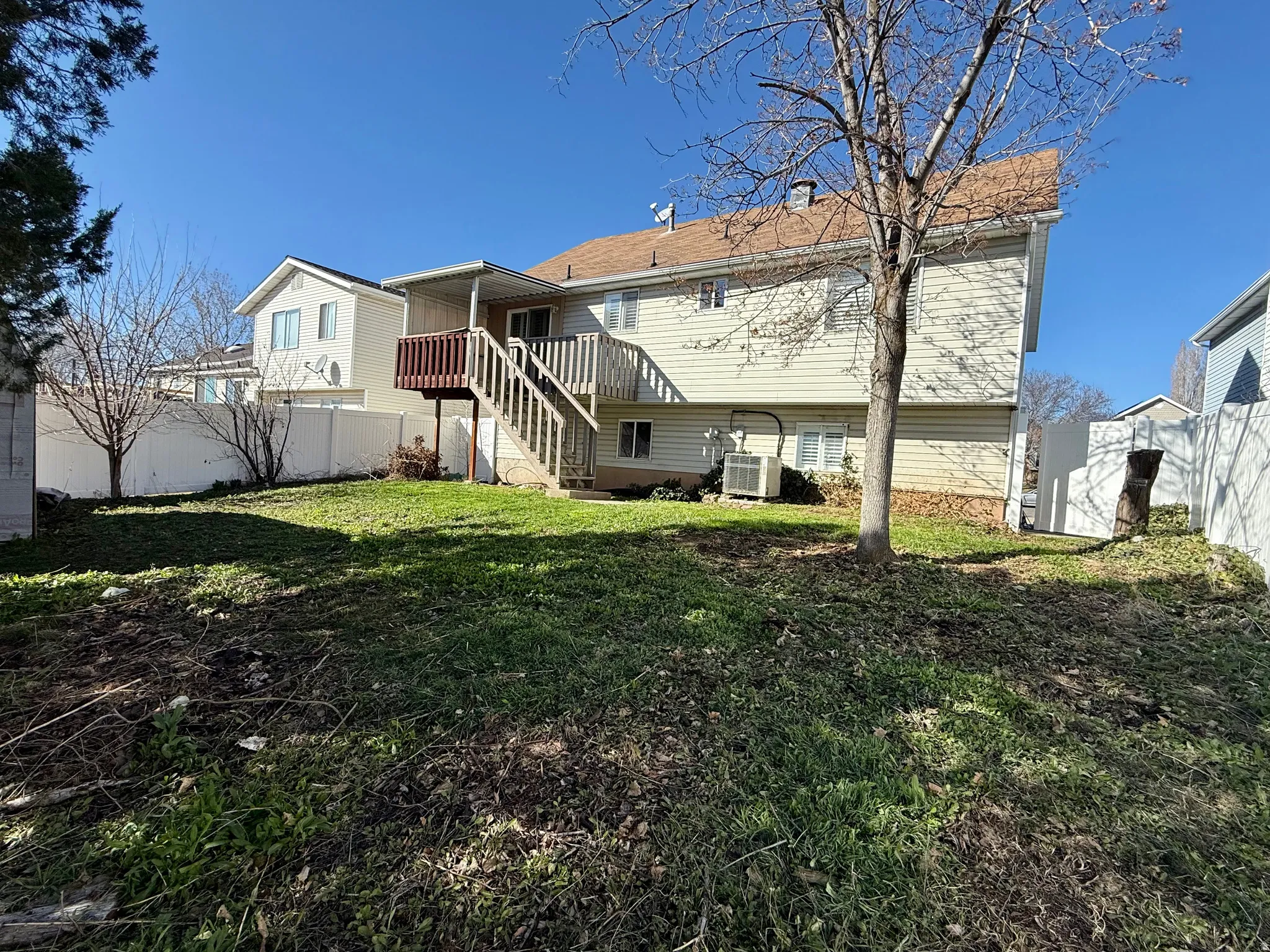 Back of property with a fenced backyard, a chimney, and a wooden deck