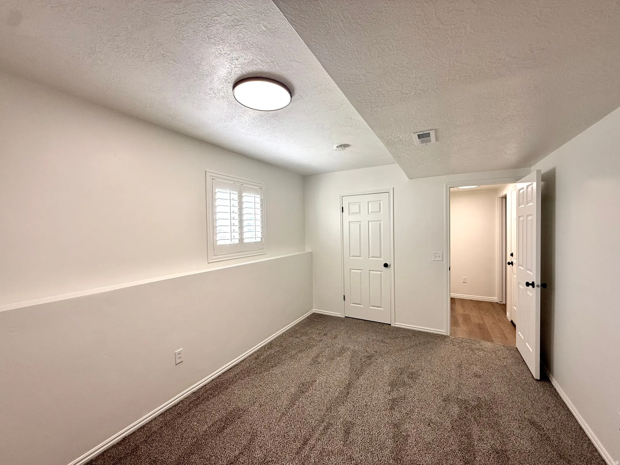 Unfurnished bedroom with a textured ceiling and dark carpet