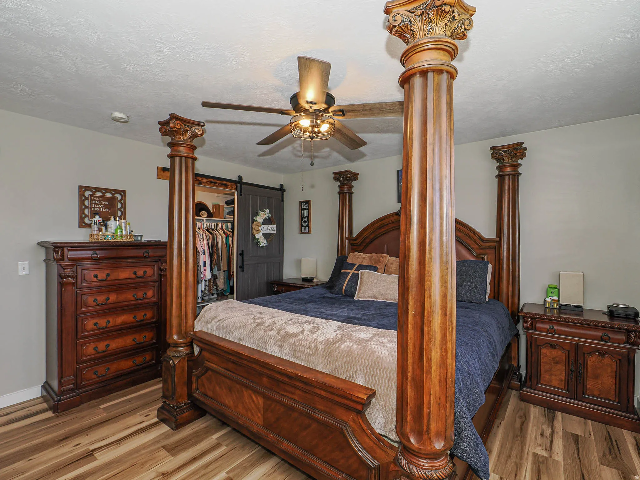 Bedroom with a spacious closet, light wood-style floors, ceiling fan, and a textured ceiling