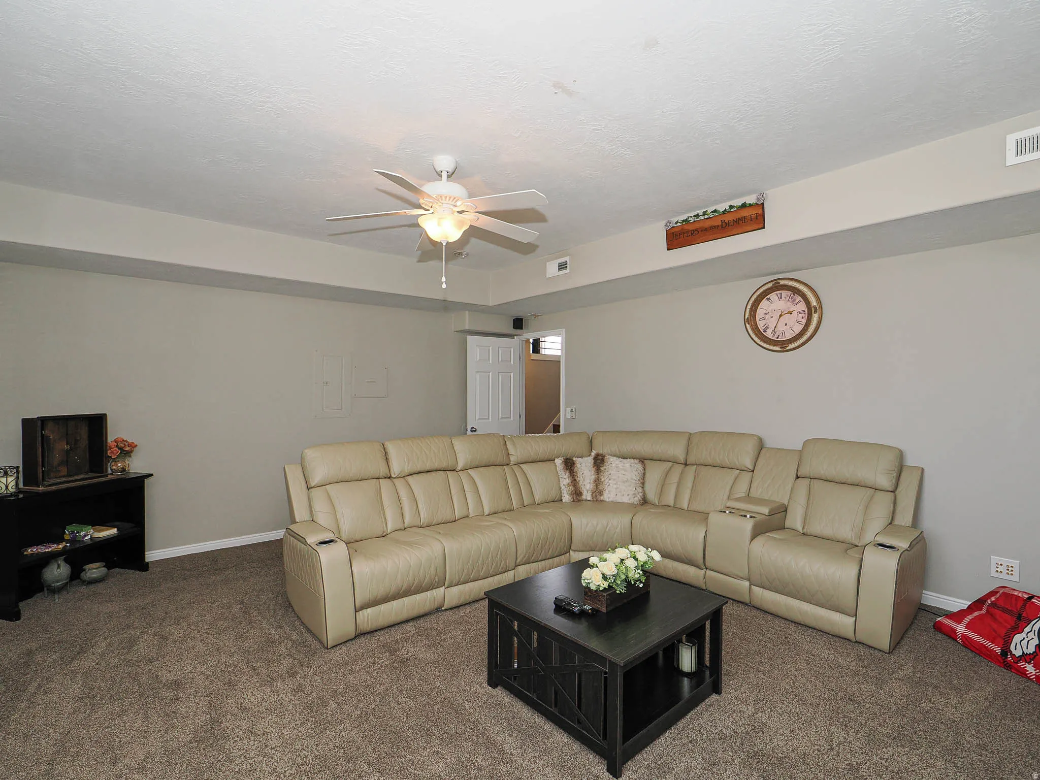 Carpeted living room with a ceiling fan and a textured ceiling