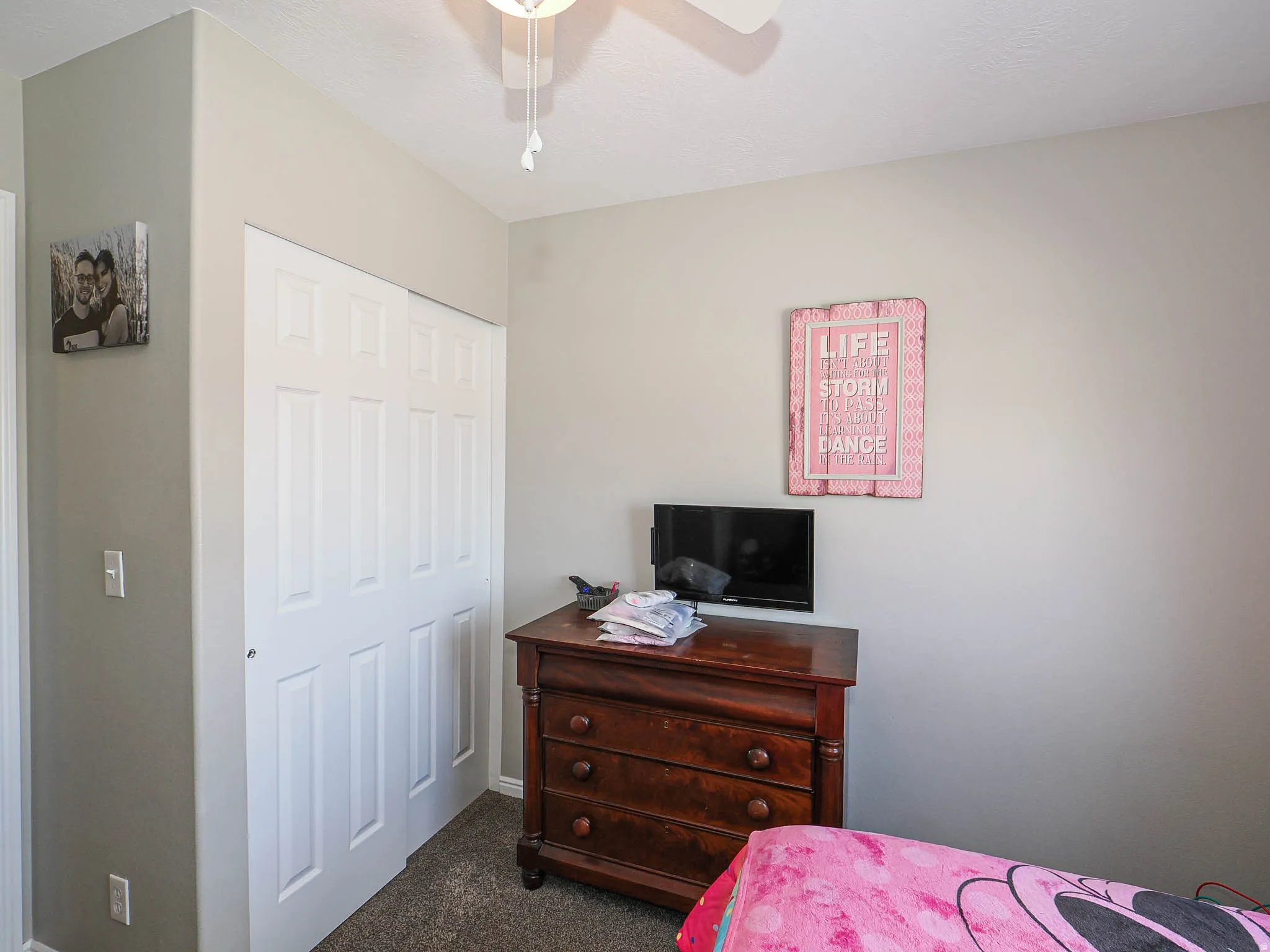 Bedroom featuring a closet, ceiling fan, and dark carpet