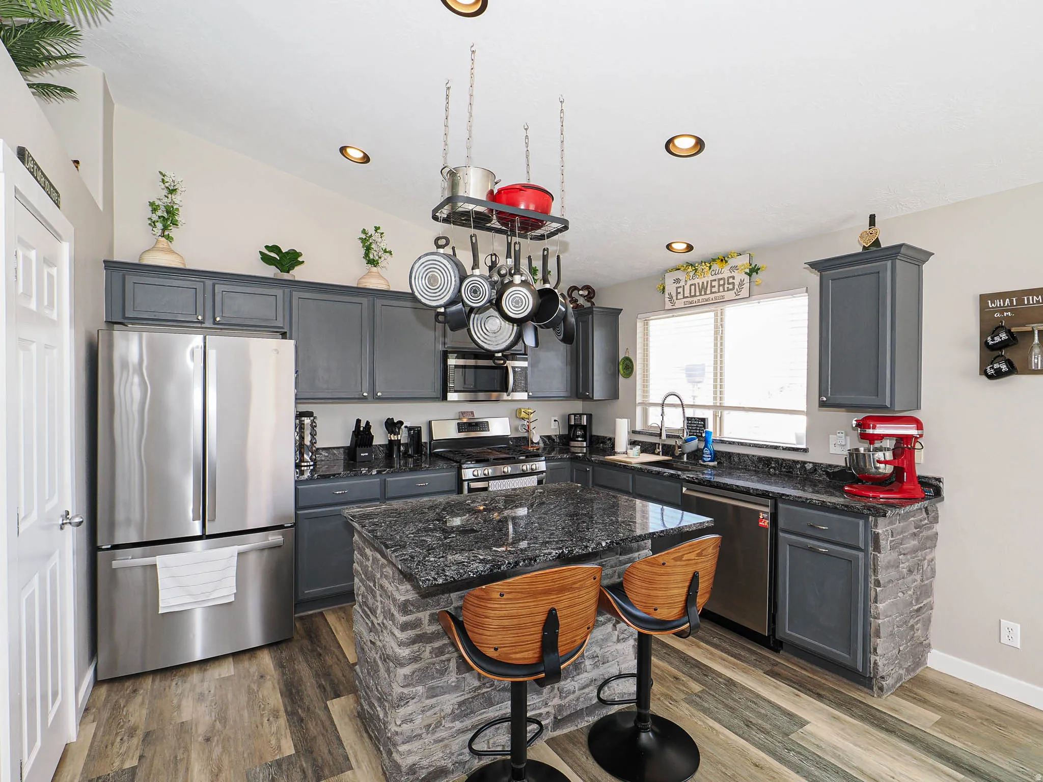 Kitchen featuring stainless steel appliances, gray cabinets, a breakfast bar, vaulted ceiling, and recessed lighting