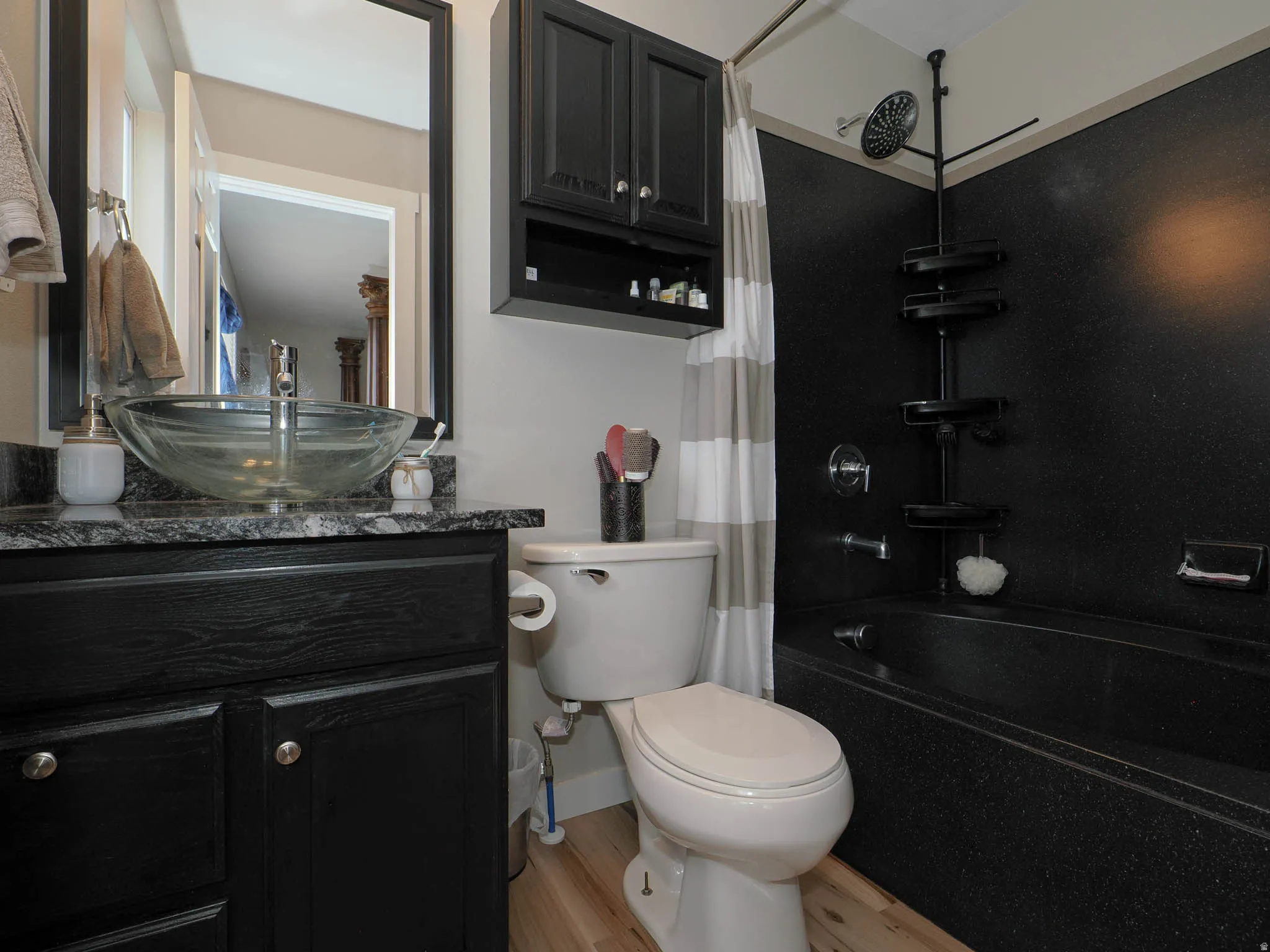 Bathroom featuring vanity, shower / tub combo with curtain, and light wood finished floors