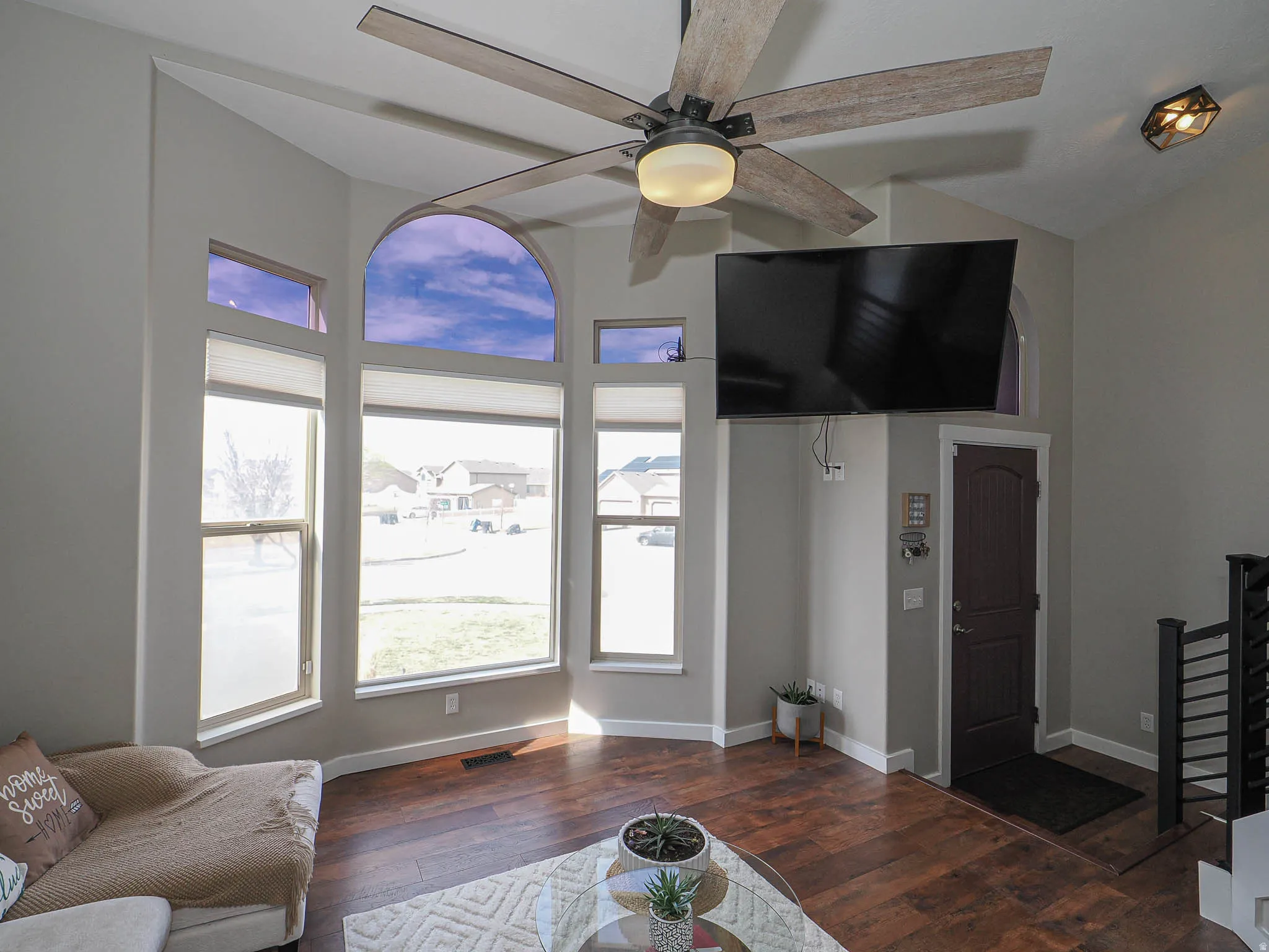 Living area with dark wood-style flooring, ceiling fan, and vaulted ceiling