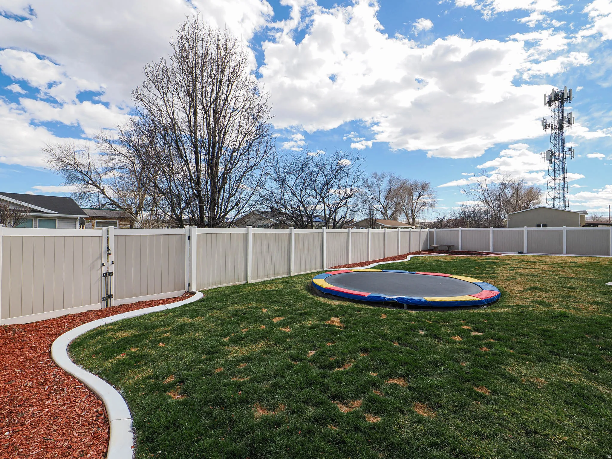Fenced backyard with a trampoline and a gate