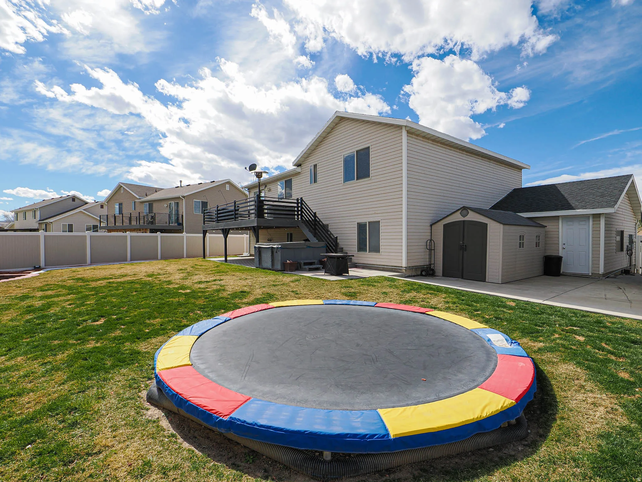 Rear view of house with a storage shed, a hot tub, a patio area, a residential view, and a wooden deck