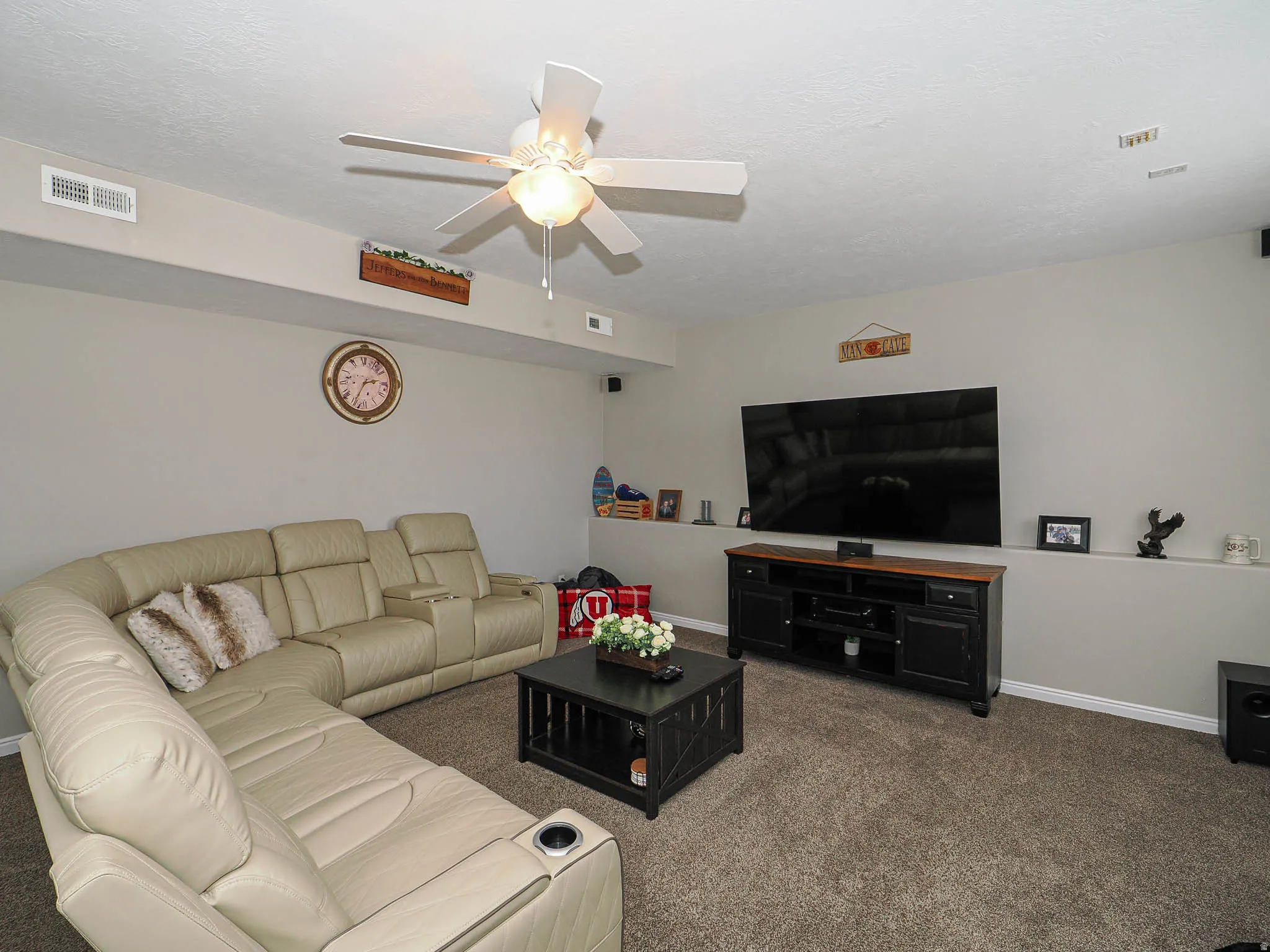 Living room with a ceiling fan and dark carpet