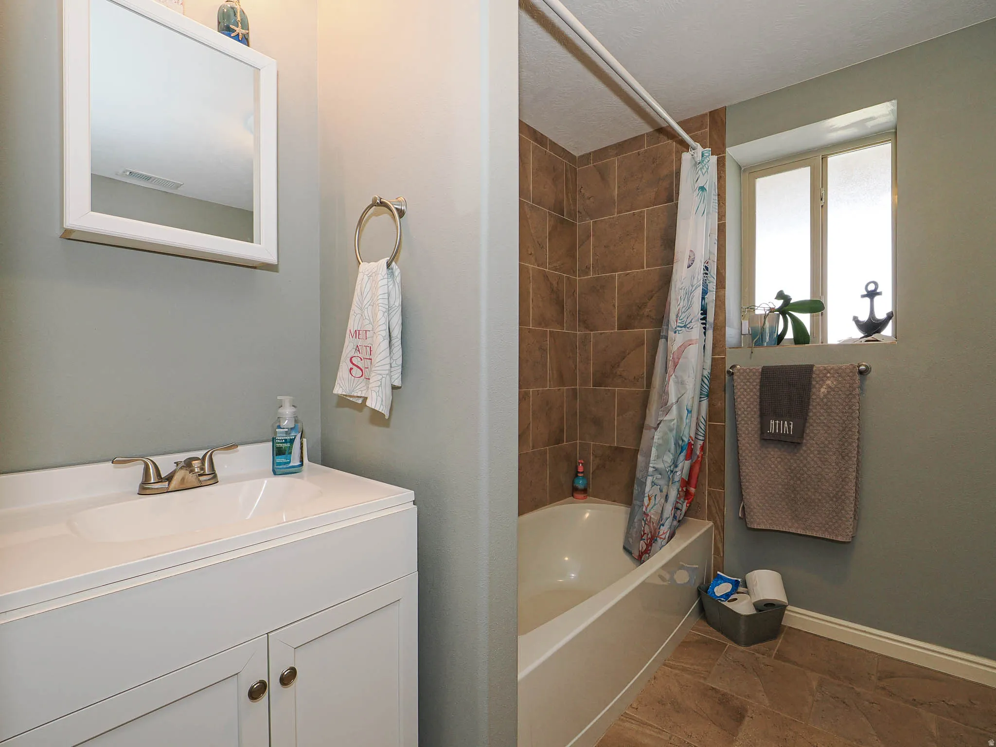 Bathroom featuring vanity and shower / bathtub combination with curtain