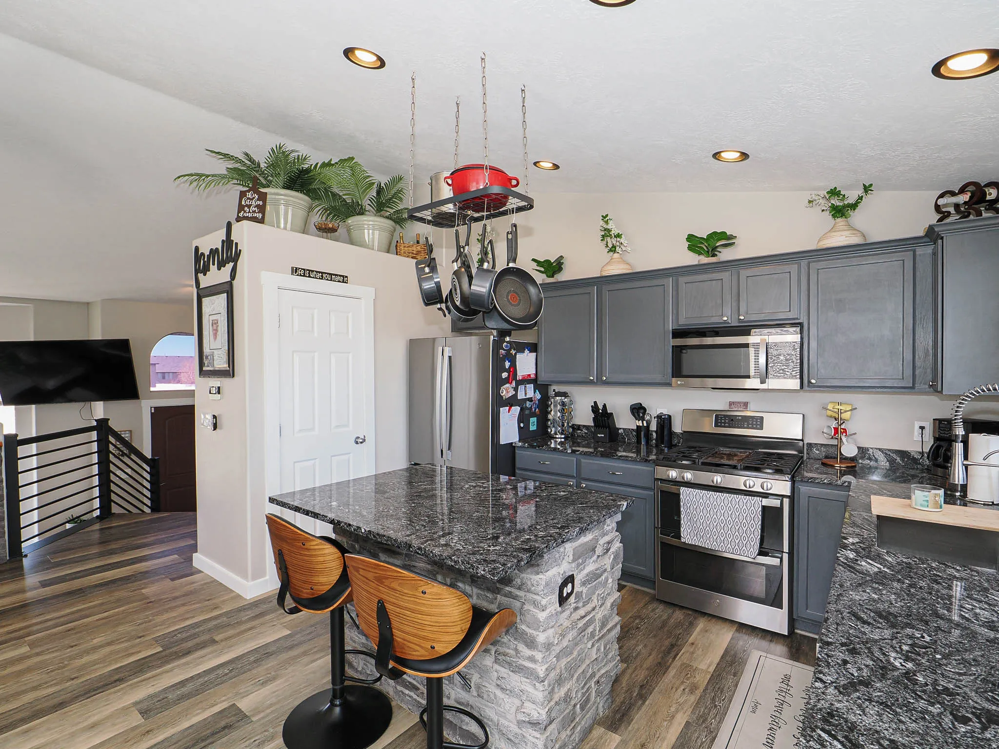 Kitchen featuring stainless steel appliances, a kitchen bar, gray cabinets, dark stone counters, and recessed lighting