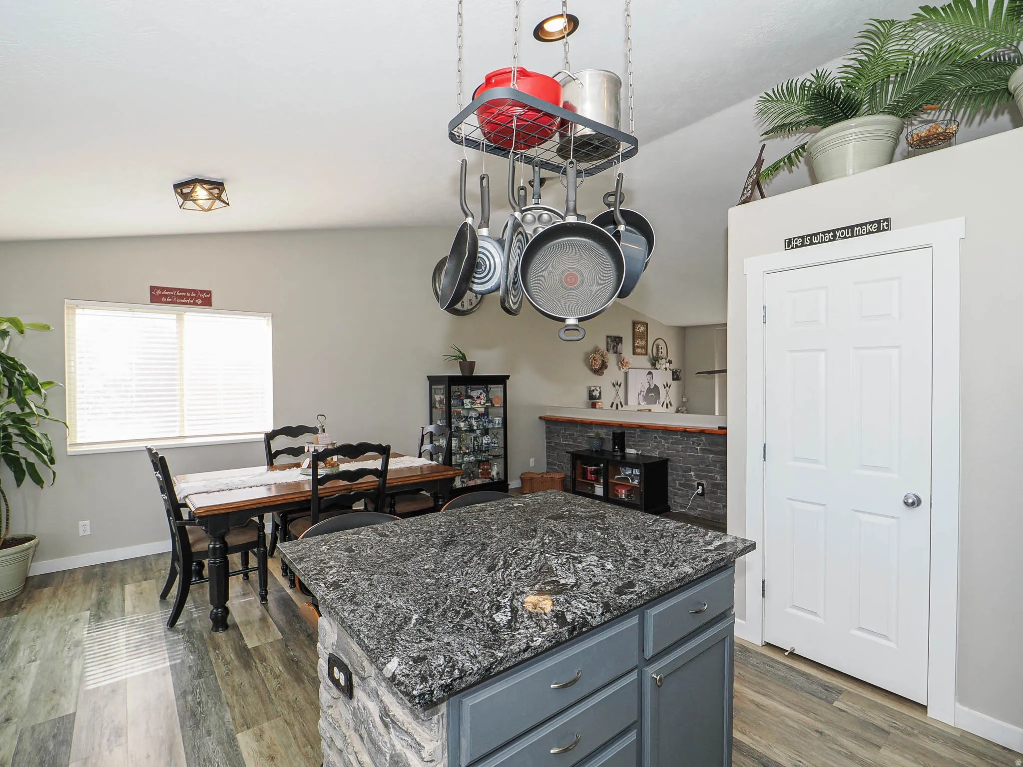 Kitchen featuring dark stone counters, dark wood-style floors, lofted ceiling, a kitchen island, and gray cabinetry