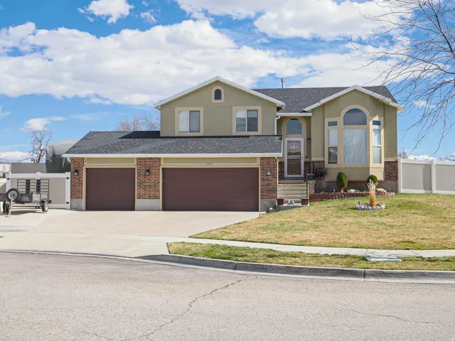Split level home featuring concrete driveway, a shingled roof, stucco siding, and an attached garage