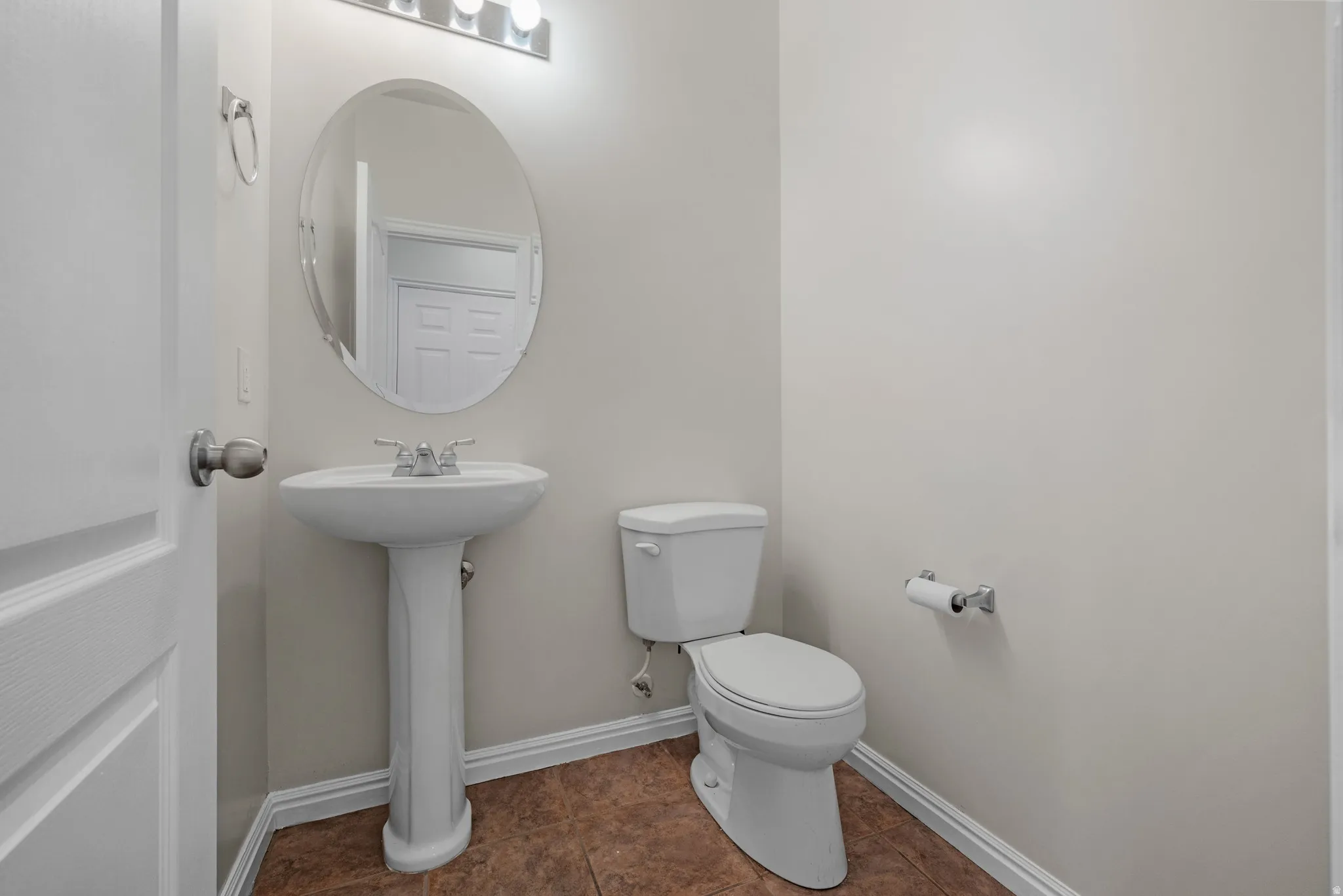 Half bathroom featuring toilet and dark tile patterned floors