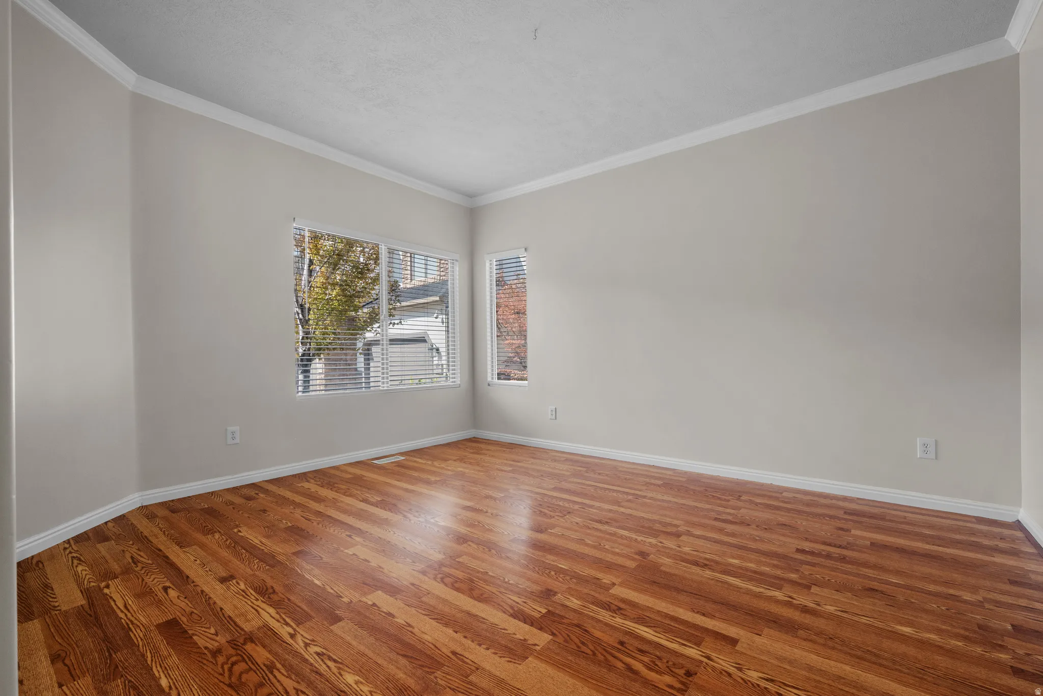 Empty room featuring ornamental molding and wood finished floors